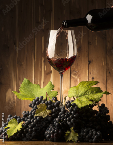 Glass with red wine and grapeson the wooden table