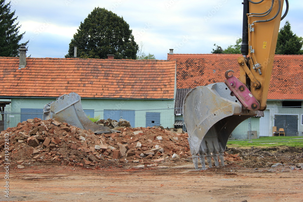Fototapeta premium Baggerschaufel auf einer Baustelle (Haus wird abgerissen)