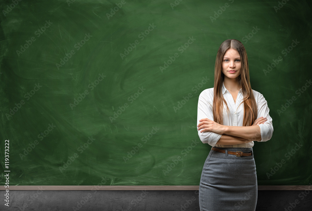 Young businesswoman with glasses standing in front of blank chalkboard Young businesswoman with glasses standing in front of blank chalkboard
