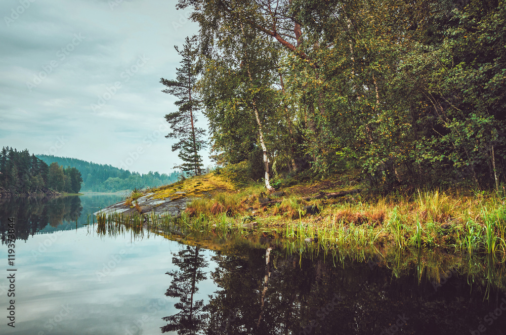Beautiful autumn landscape with lake, pine trees, natural stone coast in the Republic of Karelia, Ladoga , northern region in Russia. Fall forest, russian tourism and travel concept. Beautiful autumn landscape with lake, pine trees, natural stone coast in the Republic of Karelia, Ladoga , northern region in Russia. Fall forest, russian tourism and travel concept.
