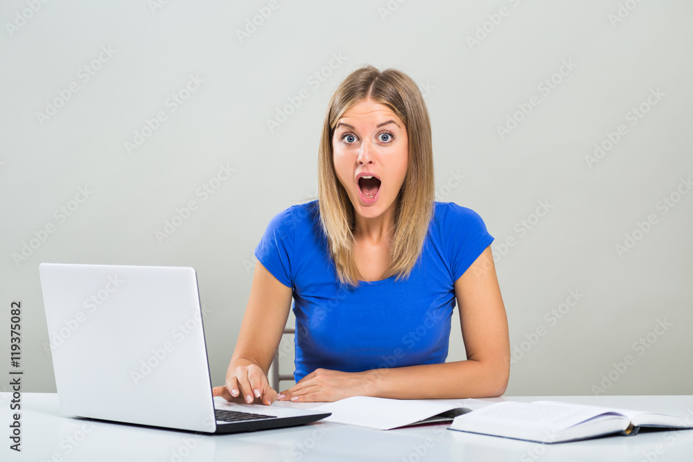 Excited female student sitting at the table,using laptop and studying.
Excited female student sitting at the table,using laptop and studying.