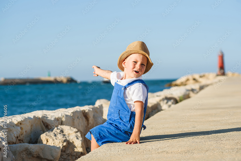 Cute blond boy in hat and blue overall