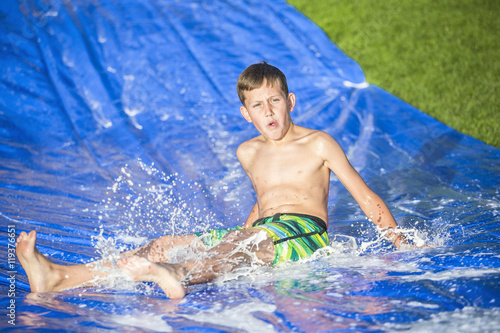 Teen boy sliding down a slip and slide outdoors