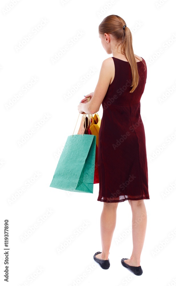 back view of woman with shopping bags. Isolated over white background. Slim blonde in a burgundy dress holding shopping bags. back view of woman with shopping bags. Isolated over white background. Slim blonde in a burgundy dress holding shopping bags.