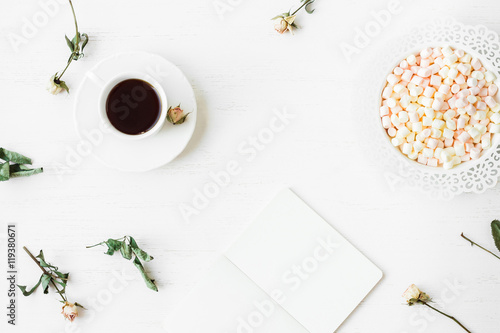 Workspace with notebook, cup of coffee and dried rose flowers. Top view, flat lay © Flaffy