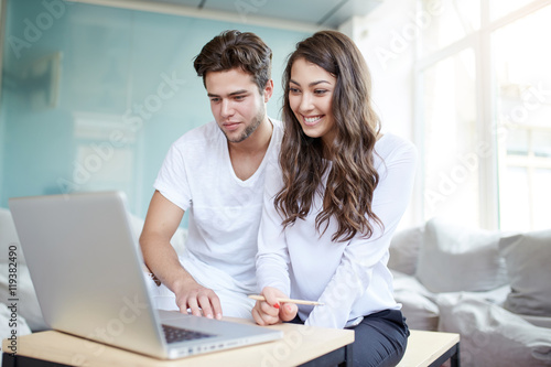 Two young business people in casual wear looking at the laptop. © basin_stock