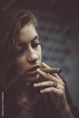 Tired woman holds Cuban cigar before her opened mouth