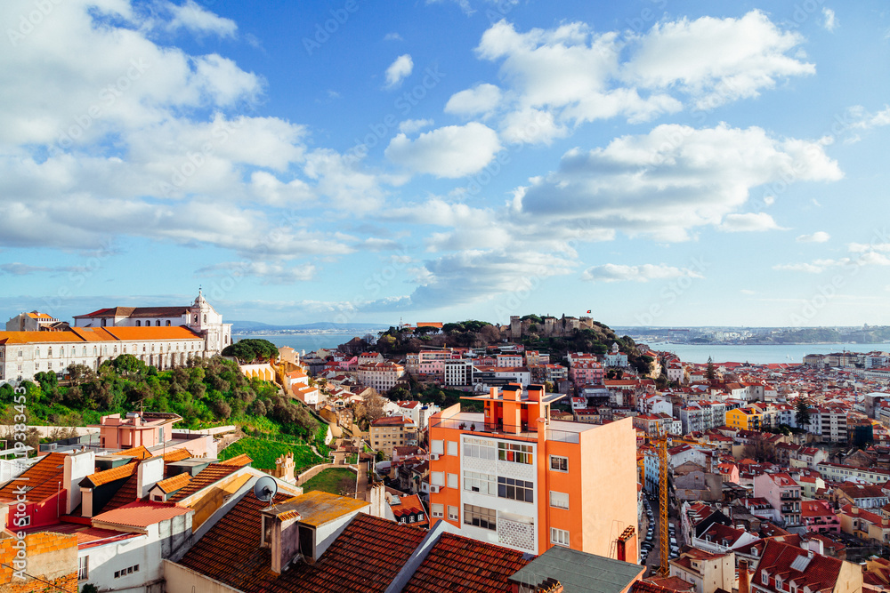 Fluffy white clouds fly over the sea city with red roofs
