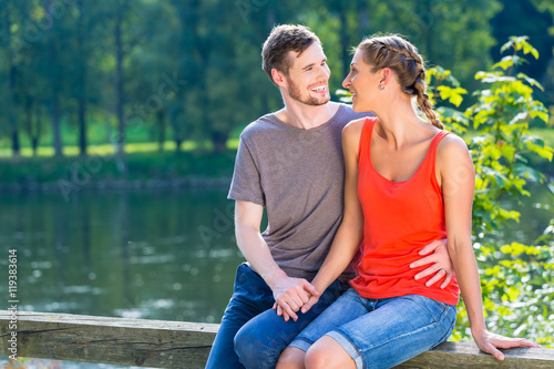Couple sitting at riverbank in summer