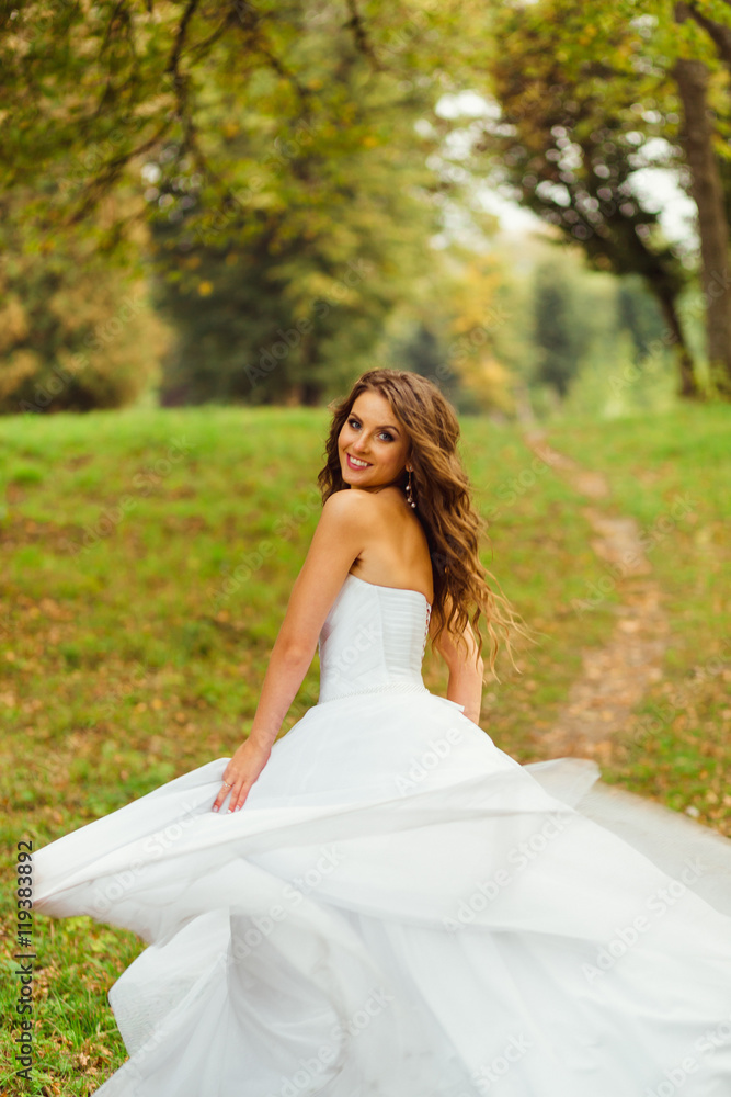 Stunning bride looks over her shoulder while whirling on the gre Stunning bride looks over her shoulder while whirling on the gre