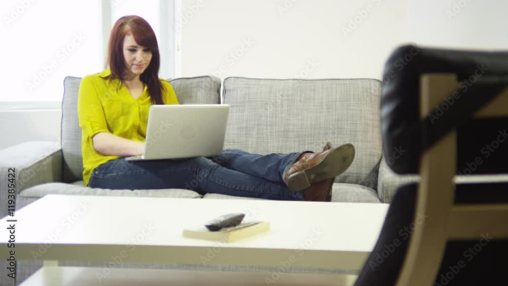 Young woman with laptop sitting in living room Young woman with laptop sitting in living room