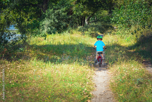 Child riding a bicycle. Kid in a helmet riding a bike in the forest. Beautiful baby. Toned image.