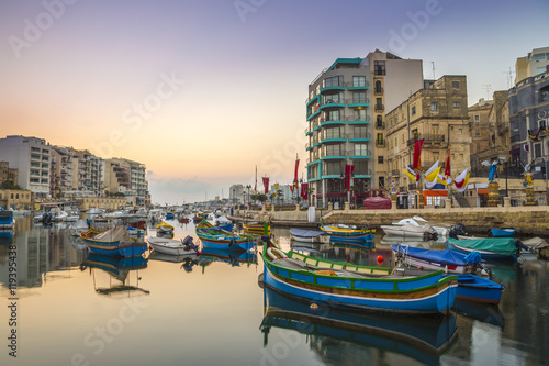 St.Julian's, Malta - Traditional colorful Luzzu fishing boats at Spinola bay on a beautiful morning sunrise