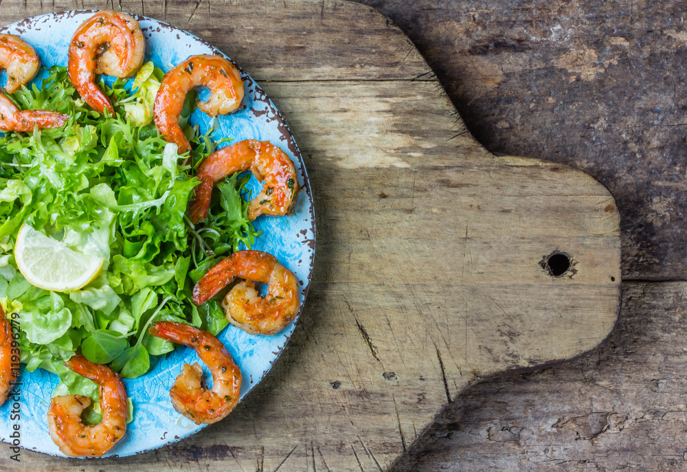 Seafood shrimp prawns lettuce salad on blue plate. Top view Seafood shrimp prawns lettuce salad on blue plate. Top view