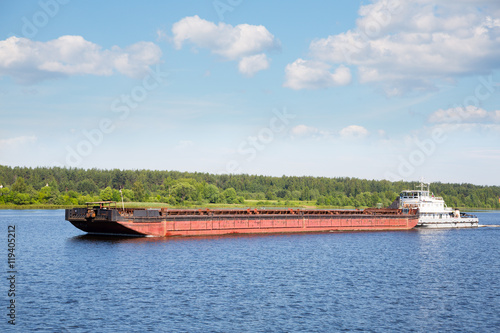 River tugboat moves cargo barge on the Volga river in the summer navigation.
