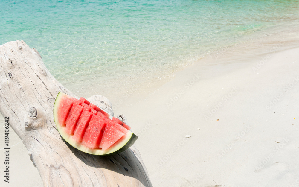 Slice of watermelon on timber against beach background. Slice of watermelon on timber against beach background.
