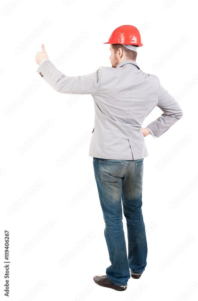 Back view of business man shows thumbs up. guy in a gray jacket and an orange helmet stands with his arms crossed.... Back view of business man shows thumbs up. guy in a gray jacket and an orange helmet stands with his arms crossed....