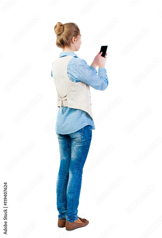 back view of standing young beautiful woman in vest and using a mobile phone. girl watching. Rear view people collection. backside view of person. Isolated over white background. Girl in back view of standing young beautiful woman in vest and using a mobile phone. girl watching. Rear view people collection. backside view of person. Isolated over white background. Girl in