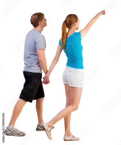 Back view of walking young couple (man and woman) pointing. going tourists in shorts considering attractions. Rear view people collection. backside view of person. Isolated over white background