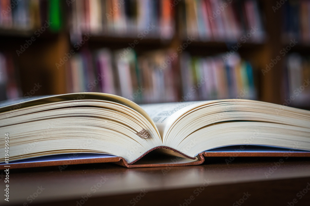Open book on the table in a library and bookshelf Open book on the table in a library and bookshelf