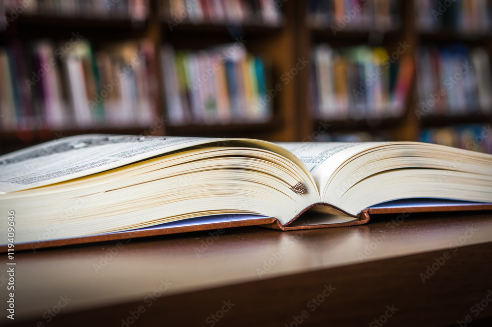 Open book on the table in a library and bookshelf Open book on the table in a library and bookshelf