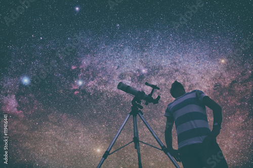 Man looking at the stars with telescope beside him. 