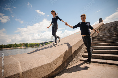 Happy young couple holding hands and running down the stairs