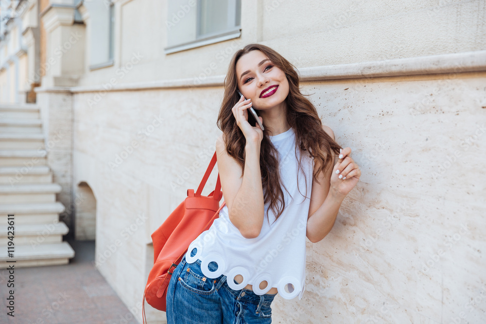 Happy girl talking on the phone standing outdoors