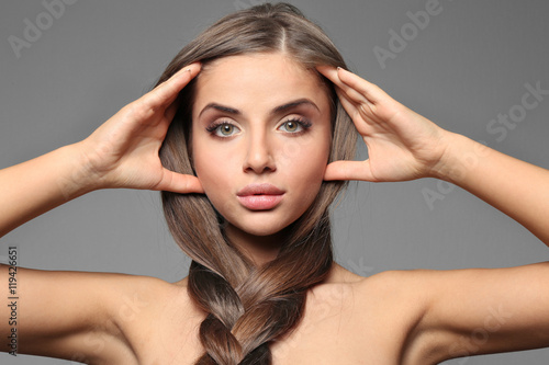 Young woman with healthy hair on color background