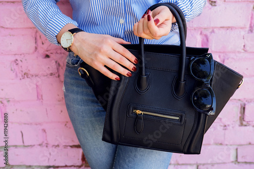 Close up black leather bag in hand of fashion woman. photo