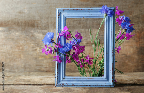 Retro frame with delphinium and bluettes on wooden background photo