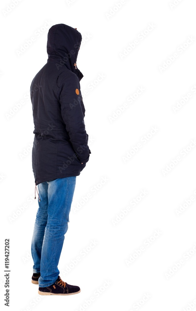 Back view of handsome man in winter jacket looking up. The guy in the stands wearing the hooded jacket left side with his hands in his pockets.
