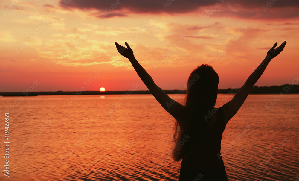 Fototapeta premium Silhouette of woman on sunset sky background