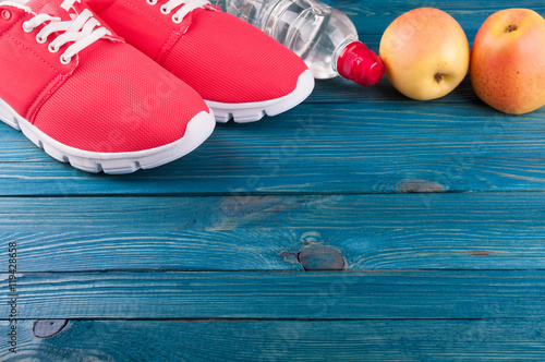 Healthy lifestyle background. Sport shoes, bottle of water and apples on wooden background. Concept healthy and sport life. Top view
