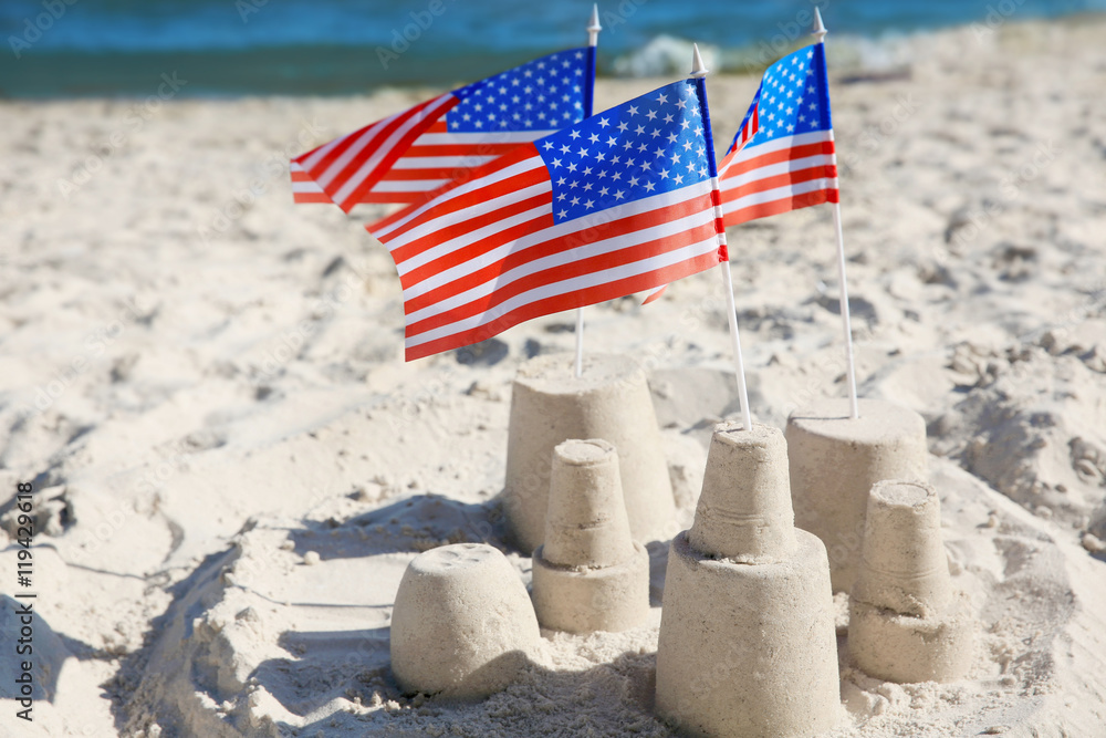 Naklejka premium Sand castle with American flags on beach