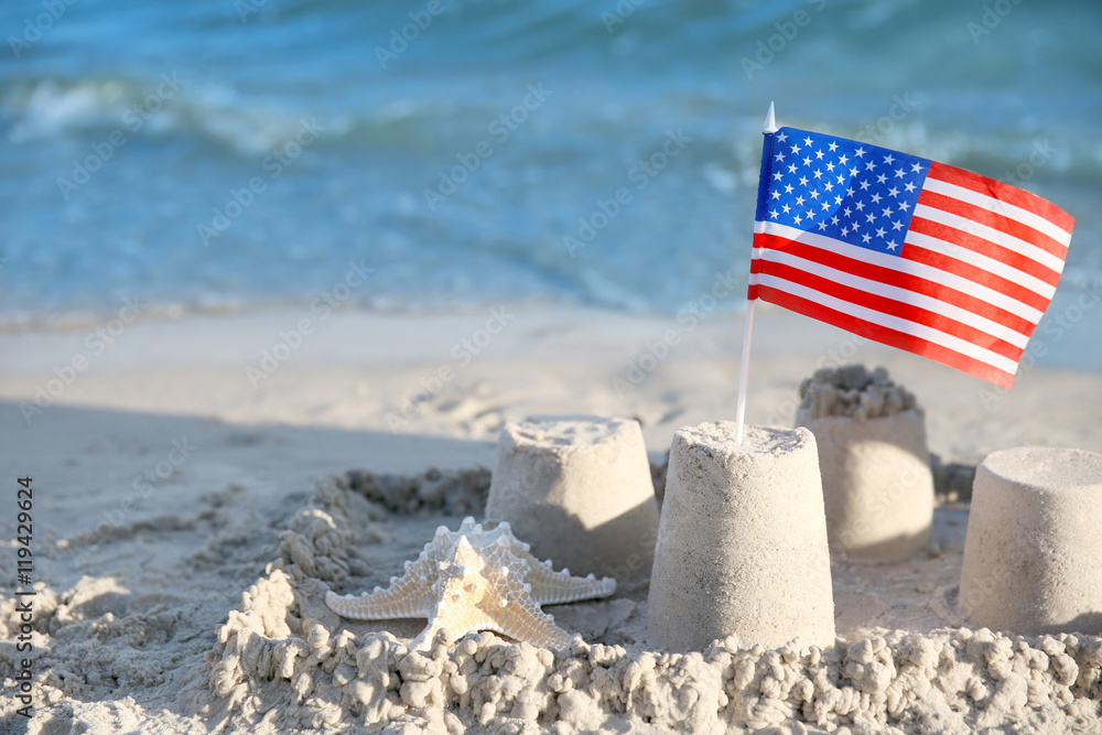 Obraz premium Sand castle with American flag on beach