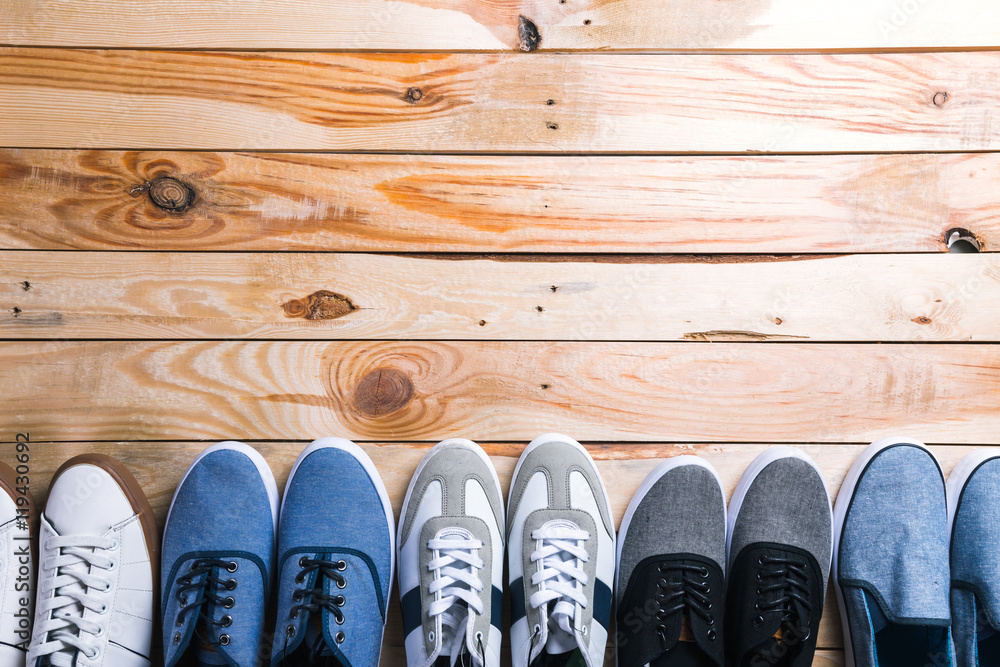 Various pairs of sneakers laid on the wooden floor background Various pairs of sneakers laid on the wooden floor background