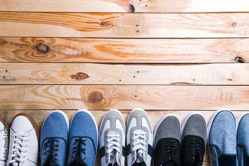 Various pairs of sneakers laid on the wooden floor background