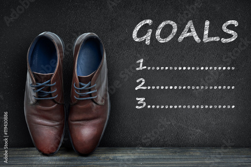 Goals text on black board and business shoes
