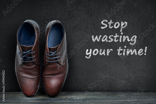 Stop wasting your time text on black board and business shoes