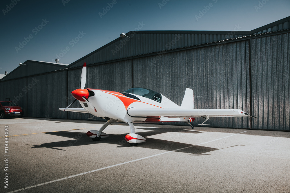 White and red small plane at the hangar's door. - obrazy, fototapety, plakaty 
