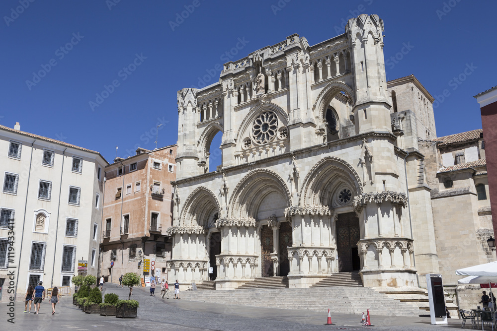 Tourists walk near the facade of the Cuenca's Cathedral, Spain