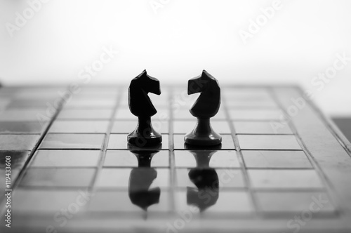 Chess is an strategy and intelligence board game originated in India that is played between two people on a chessboard. Knights face to face. photo