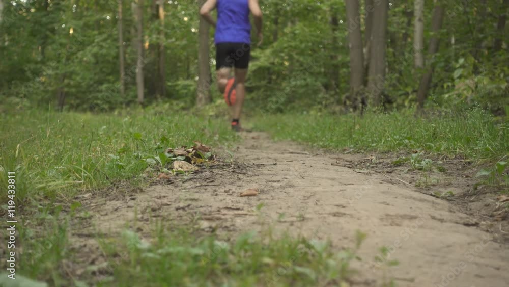Man running cross country  in summer forest. Jogging motivation in green park beautiful inspirational landscape .