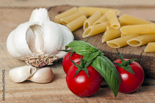 pasta, tomato and garlic on wood background