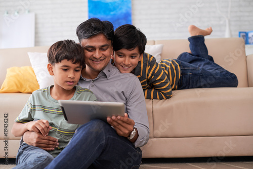 Father and sons enjoying movie on digital tablet