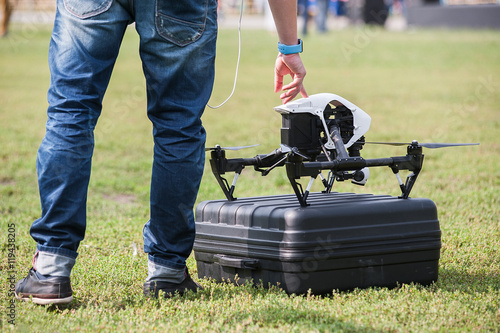 Man presses start button on drone/Man presses a button to launch drone with camera at stadium