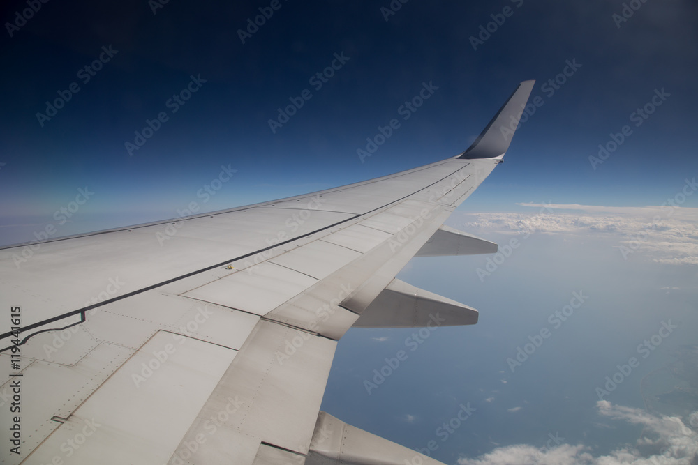 Wing of an airplane flying above the clouds. people look at the sky from the window of the plane, using air transport to travel. back light sun beam