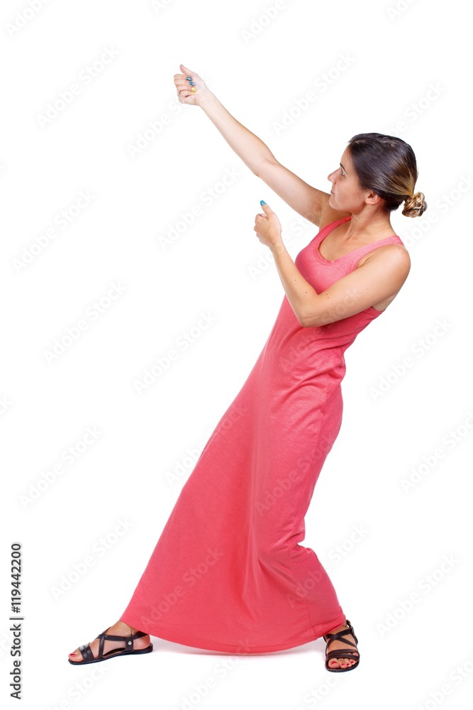 back view of standing girl pulling a rope from the top or cling to  something. A slender woman in a long red dress pulls a rope from the top  Stock Photo