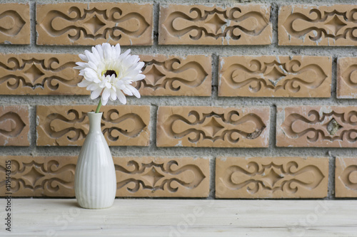 Flowers in a vase on a brick wall